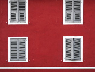 red house facade with white windows (Corte, Corsica, France).