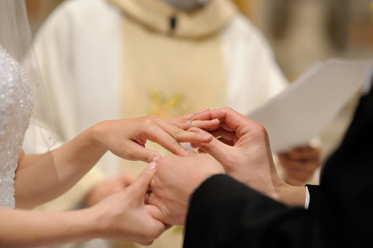 Groom putting a ring on bride's finger