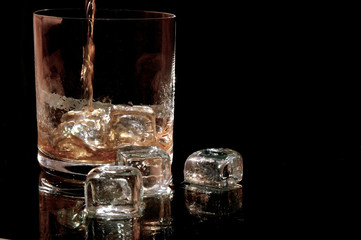 Whiskey fließt in ein Glas mit Eiswürfeln