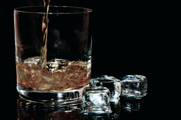 Whiskey fließt in ein Glas mit Eiswürfeln