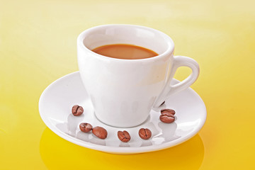 Small white cup of coffee with coffee grain on yellow background