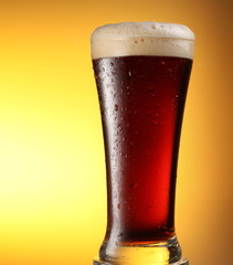 glass of dark beer on a yellow background