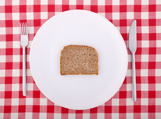 Tablecloth with fork, knife and a slice of bread on the plate