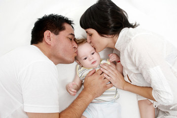 baby with parents lying on a bed