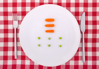 Tablecloth with fork, knife, six peas and three carrotts on the