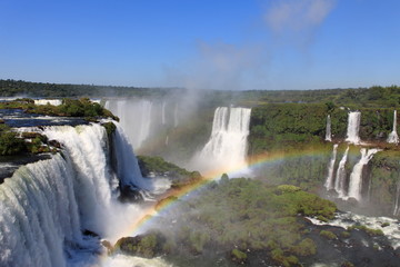 Iguazu waterfalls with rainbow on a sunny day.