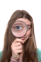 The girl holds a magnifier at an eye