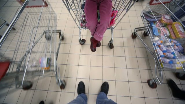 buyers with shopping trolley going in mall, view on floor