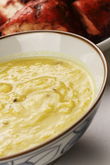 A bowl of Dhal with Tandoori Chicken in the background