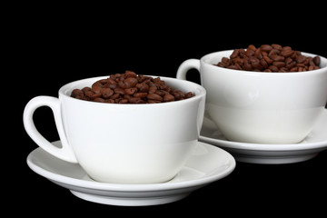 Two white cups, full of coffee beans