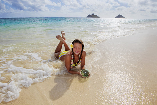 teenage girl lying on a beach in hawaii with glass fishnet ball
