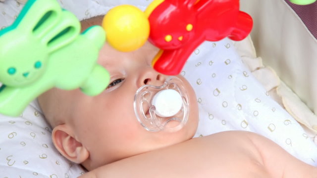 baby laying in the crib with toys