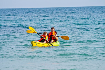 father and son are padelling with a canoe on open sea