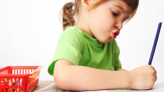 small girl sits at table, paints by pencil picture and talk