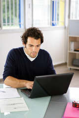 Portrait d'un jeune homme devant ordinateur portable au bureau