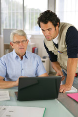 Portrait de deux hommes devant ordinateur portable au bureau