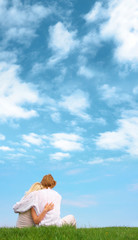 Guy and girl sitting on the ground beneath the cloudy sky