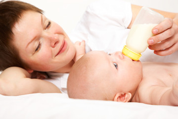 Obraz na płótnie Canvas young mother feeding baby with a bottle