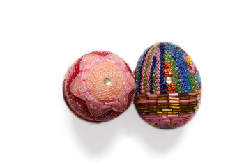 Two eggs decorated with tiny beads on white background