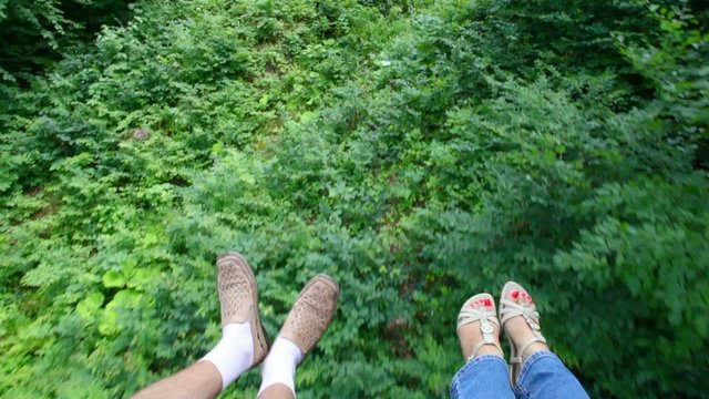 feet of tourists moving on funicular above forest