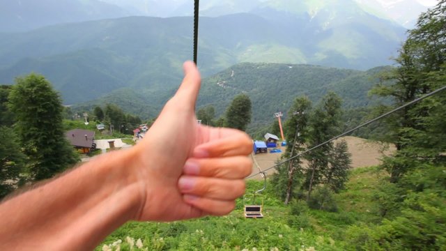 moving funicular in mountains, two hands giving thumbs up
