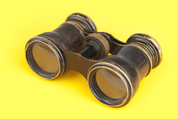 Old binoculars on yellow background