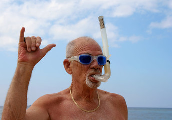 Active senior with dive mask giving friendly shaka wave