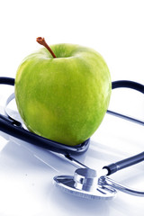Stethoscope and green apple on white background
