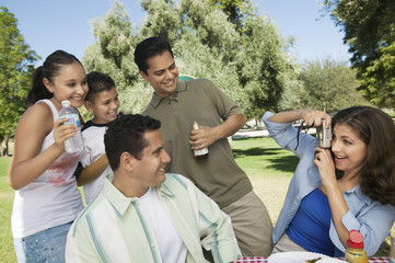 woman using digital camera photographing son (13-15) with father brother and sister.