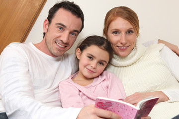 Jeune couple lisant un livre à une fillette