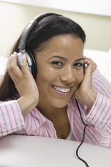 woman lying on sofa listening to music on headphones portrait