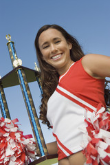 smiling cheerleader holding trophy (portrait) (low angle view)