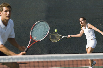Fototapety  mieszany gracz deblowy uderzający partnera z piłką tenisową stojącego w pobliżu siatki