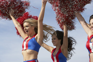 cheerleaders running holding pom poms in air