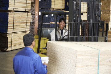 workers with forklift carrying wood in warehouse