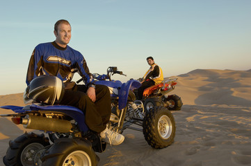 men standing by quad bikes in desert © MDBPIXS