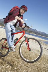 young man riding mountain bike on lake shore