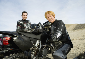 motocross racers with bike outdoors (portrait)