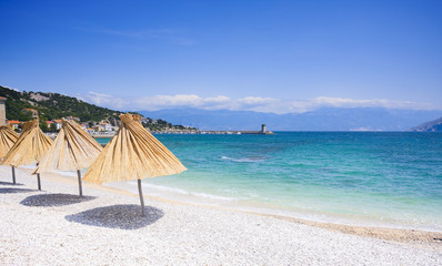 straw gamps lined up on the shingly beach in Baska, Croatia