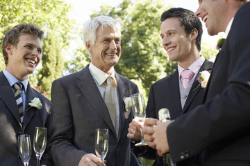 four men holding empty wineglasses smiling