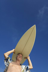 male surfer carrying surfboard on head (low angle view)