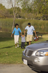 family walking by river behind car