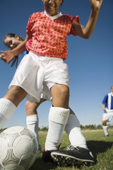 girls (13-17) playing soccer one tackling another low angle view cropped