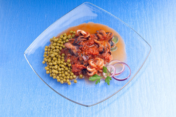 dish with octopus with tomato sauce and peas