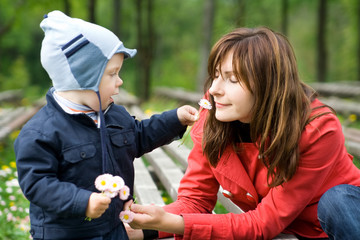 Spring. Mother and little son smell flowers