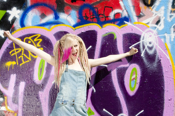 portrait of young woman standing at graffitti wall