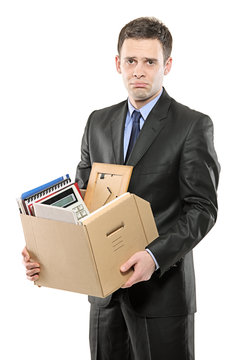 A fired man in a suit carrying a box of personal items