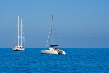 Yacht and catamaran on blue sea