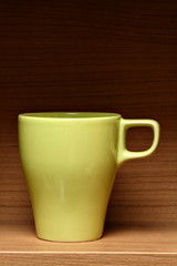 Light green coffee cup on wooden shelf