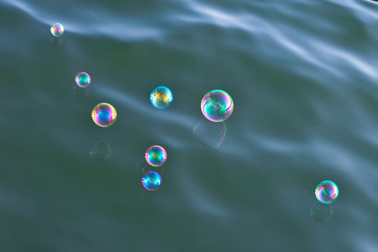 Mehrere, in allen Farben schillernde Seifenblasen über einem See